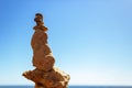 A pyramid of sea pebbles on a sunny sandy beach against a blue sky. The concept of life balance Royalty Free Stock Photo