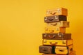 pyramid of several vintage suitcases on a yellow background