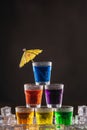 Pyramid of shots with colorful alcohol, decorated with umbrellas for cocktails