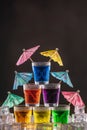 Pyramid of shots with colorful alcohol, decorated with umbrellas for cocktails