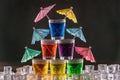 Pyramid of shots with colorful alcohol, decorated with umbrellas for cocktails