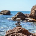 Pyramid stones balance on the sand of the beach. Blue Sea on Background Selective focus, zen stones on sea beach, meditation, spa Royalty Free Stock Photo