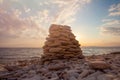 Pyramid of stones on the beach at sunset, beautiful seascape, rest and seaside vacation concept