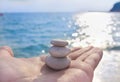 Pyramid of stones on hand palm sea glare water background