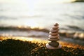 Pyramid of stones lies on the seashore in the rays of the setting sun