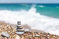 Pyramid of stones near the ocean. Obo from pebbles. Stone tower on the beach, blue waves behind. Balance, peace of mind Royalty Free Stock Photo