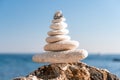 Pyramid stones on the seashore on a sunny day on the blue sea background. Happy holidays. Pebble beach, calm sea, travel