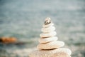 Pyramid stones on the seashore on a sunny day on the blue sea background. Happy holidays. Pebble beach, calm sea, travel