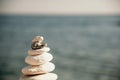 Pyramid stones on the seashore on a sunny day on the blue sea background. Happy holidays. Pebble beach, calm sea, travel