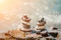 Balanced rock pyramid on pebbles beach, sunny day and clear sky at sunset. Golden sea bokeh on background. Selective