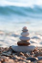 Pyramid of stones stacked on the seashore in the rays of the setting sun