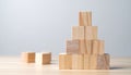 A pyramid structure built with wooden blocks on a wooden surface, with a few blocks offset to the side. The light and minimalist Royalty Free Stock Photo