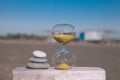 A pyramid of three stones next to an hourglass, stand on a wooden board on a blurred background Royalty Free Stock Photo