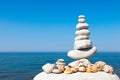 Pyramid of white stones and shells on a background of blue sky and sea