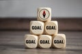 Pyramide made of cube and dice with words Goal and compass icon on wooden background