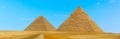 Pyramids at Giza, Egypt protrude majestically into a blue cloudless sky