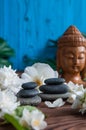 Pyramids of gray zen stones with white flowers, green leaves on wooden background. Concept of harmony, balance and meditation,