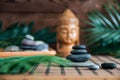 Pyramids of gray zen stones with green leaves and Buddha statue. Concept of harmony, balance and meditation, spa, massage, relax Royalty Free Stock Photo