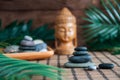 Pyramids of gray zen stones with green leaves and Buddha statue. Concept of harmony, balance and meditation, spa, massage, relax Royalty Free Stock Photo