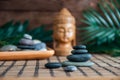 Pyramids of gray zen stones with green leaves and Buddha statue. Concept of harmony, balance and meditation, spa, massage, relax Royalty Free Stock Photo