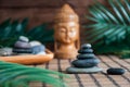 Pyramids of gray zen stones with green leaves and Buddha statue. Concept of harmony, balance and meditation, spa, massage, relax Royalty Free Stock Photo