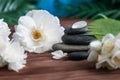 Pyramids of gray zen stones with white flowers, green leaves on wooden background. Concept of harmony, balance and meditation, Royalty Free Stock Photo