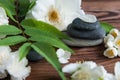 Pyramids of gray zen stones with white flowers, green leaves on wooden background. Concept of harmony, balance and meditation, Royalty Free Stock Photo