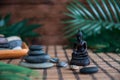 Pyramids of grey zen stones with green leaves and Buddha statue. Concept of harmony, balance and meditation, spa, massage, relax Royalty Free Stock Photo