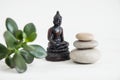Pyramids of white zen stones with green leaves and Buddha statue. Concept of harmony, balance and meditation, spa, massage, relax Royalty Free Stock Photo