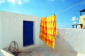 Pyrgos, Santorini / Greece: An orange and yellow bedspread, hanging to dry on a rooftop in the village of Pyrgos,