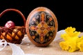 Pysanka, painted eggs in busket and spring daffodils. Easter eggs on black background. Holiday concept. Ethnic easter Royalty Free Stock Photo