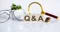 Q A concept on the wooden cubes and flower ,glasses ,coins and magnifier on white background