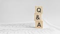 Q and A - letters on wooden cubes. concept on cubes and diagrams on a gray background. Business as usual concept imag.