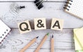 Q and A text on wooden block with office tools on wooden background