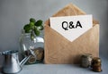 Q AND A text is written on white paper on an antique envelope, which lies on the table along with a stack of coins, a glass jar of Royalty Free Stock Photo