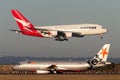 Qantas Airbus A380 large four engined passenger aircraft landing at Sydney Airport while a Jetstar aircraft is on the tarmac
