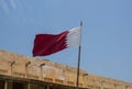 Qatari Flag flying over traditional Arabic building