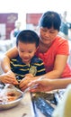Qingyuan, China - June 23, 2016: Grandmother is teaching grandson to cook chinese traditional food zhongzi