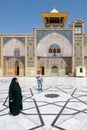 Qom, Iran - 04.20.2019: Islamic woman in tradiitonal black dress walking under in the courtyard of Fatima Masumeh Shrine. Hazrat