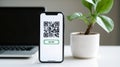 Qr code scan on smart phone screen with laptop and green plant Royalty Free Stock Photo