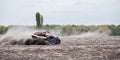 Quad bike quickly rides in dust clubs over plowed field