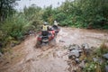 Quad rider jumping on a muddy forest trail