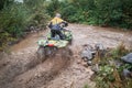 Quad rider jumping on a muddy forest trail