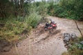 Quad rider jumping on a muddy forest trail