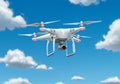 Quadcopter drone in flight against a blue sky with white clouds. Royalty Free Stock Photo