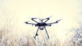 Quadcopter drone hovering in a clear blue sky and landing on the ground, video and photo shooting concept. Clip. Black Royalty Free Stock Photo