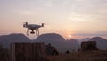 Quadcopter Drone Taking Off in Park at Beautiful Sunrise with Mountains on Background. Phang Nga, Thailand.