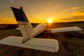 Quadruple aircraft parked at a private airfield. Rear view of a plane with a propeller on a sunset background.