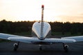 Quadruple aircraft parked at a private airfield. Rear view of a plane with a propeller on a sunset background.