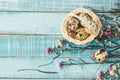 Quail eggs in basket and flowers on blue wood